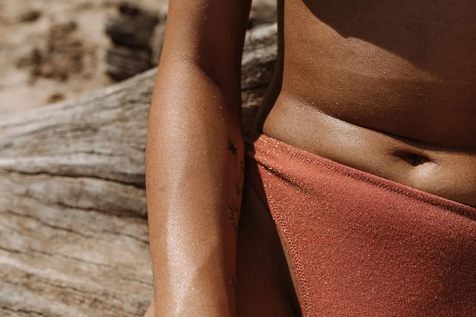 Detailed close-up of a woman in a shimmering swimsuit enjoying a sunny day at the beach.